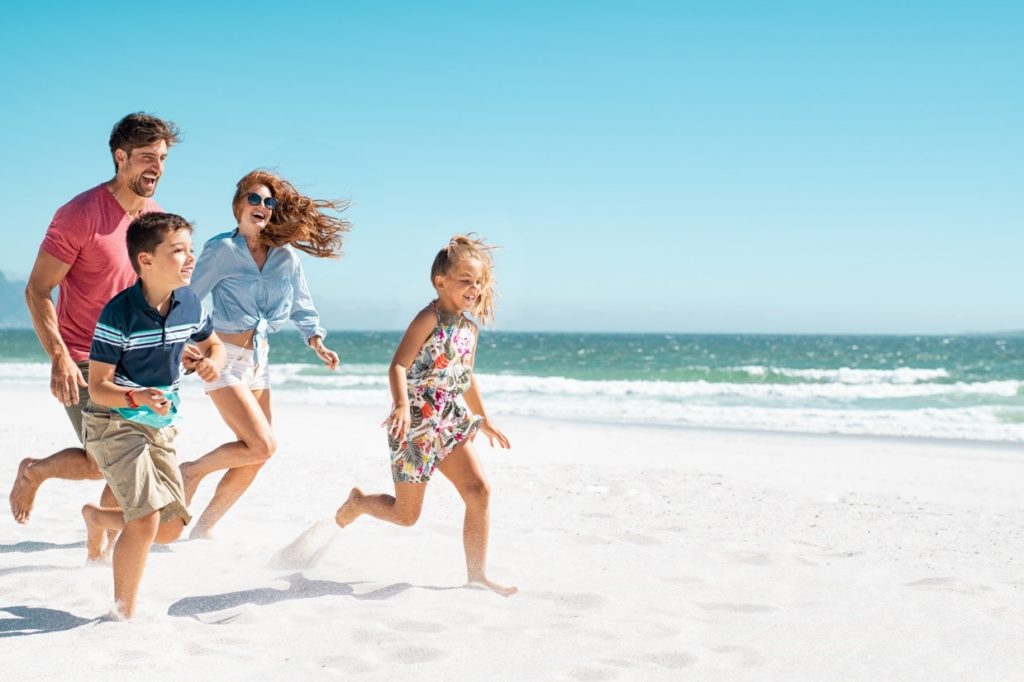 rodzina z dwójką dzieci biegnąca po plaży