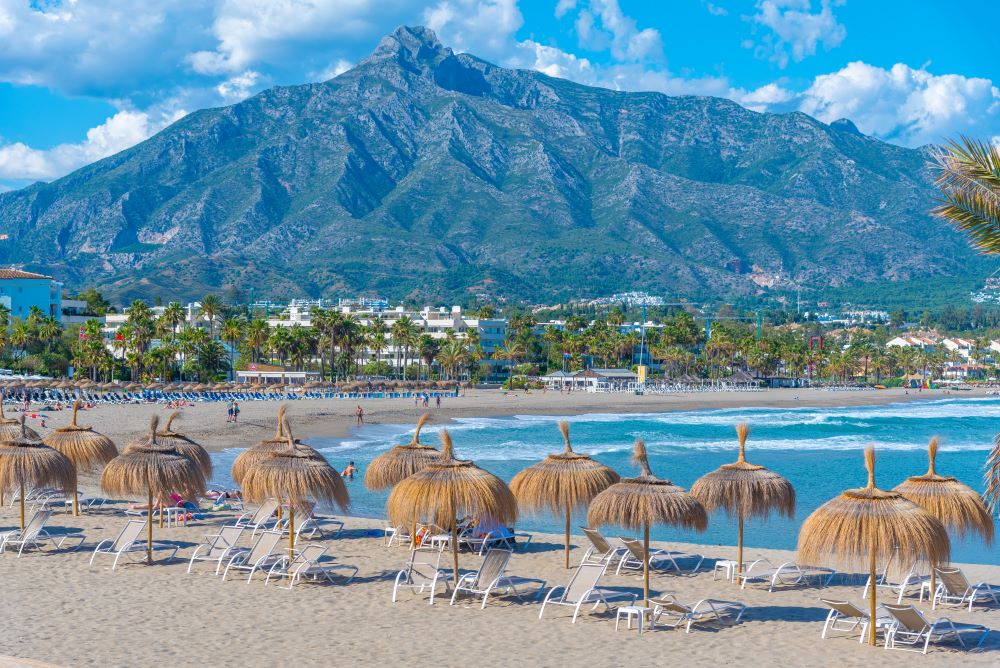 Widok na plażę z leżakami i parasolami w Marbelli, Costa del Sol.